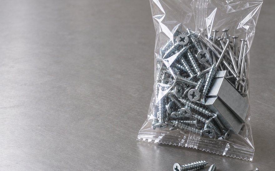 Dikey paketleme makinesinde şeffaf poşete doldurulmuş vida, çivi ve zımba teli